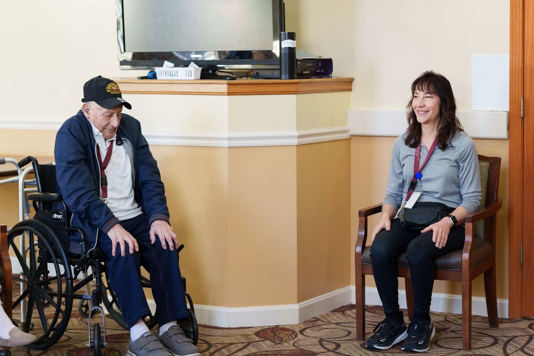 A man in a wheelchair is sitting next to a woman in a chair.