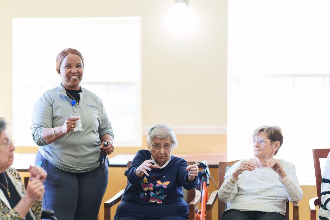 A group of elderly women are sitting in chairs in a room.