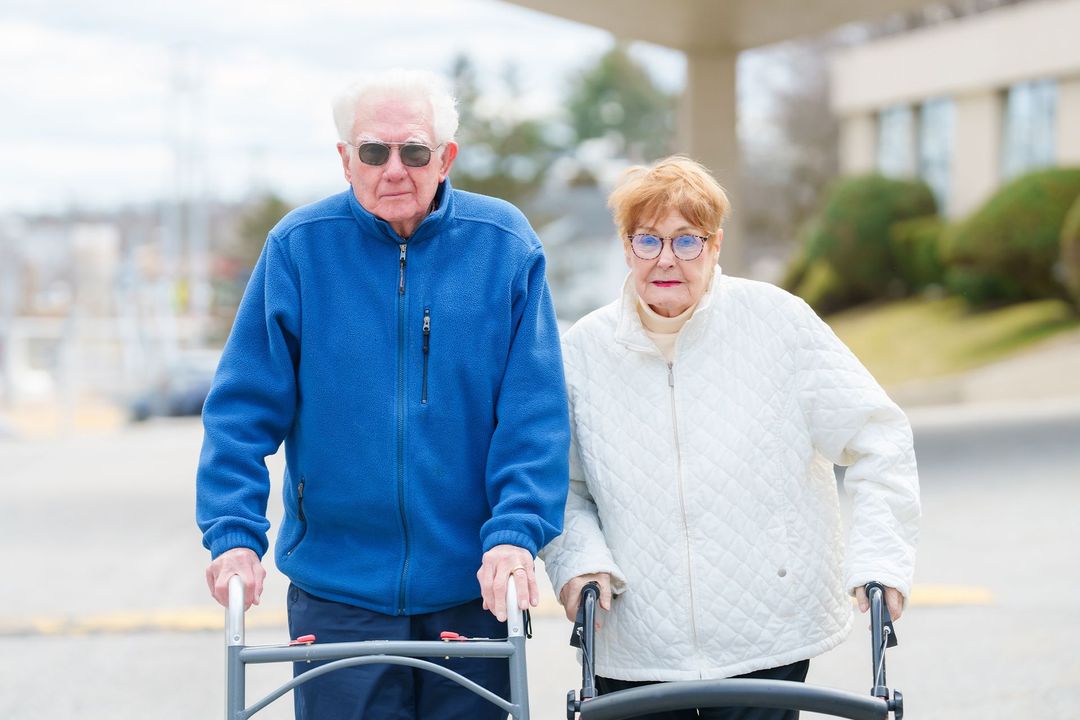 A man and a woman are standing next to each other with a walker.