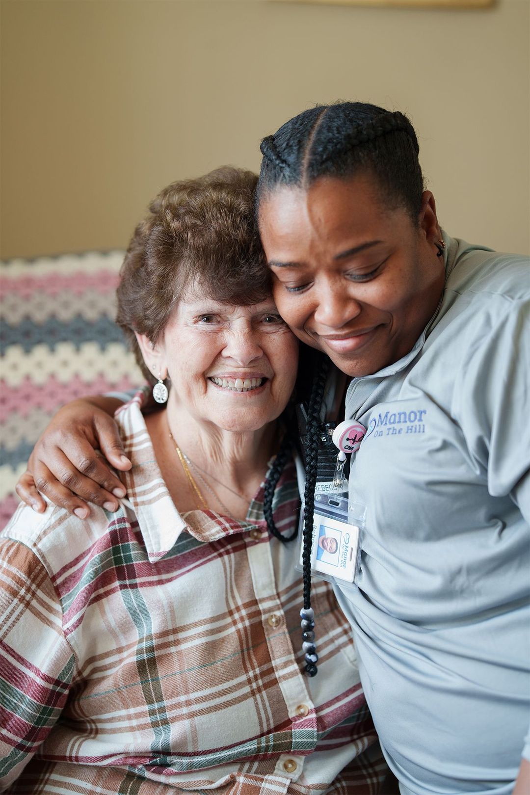 A nurse is hugging an elderly woman in a chair.