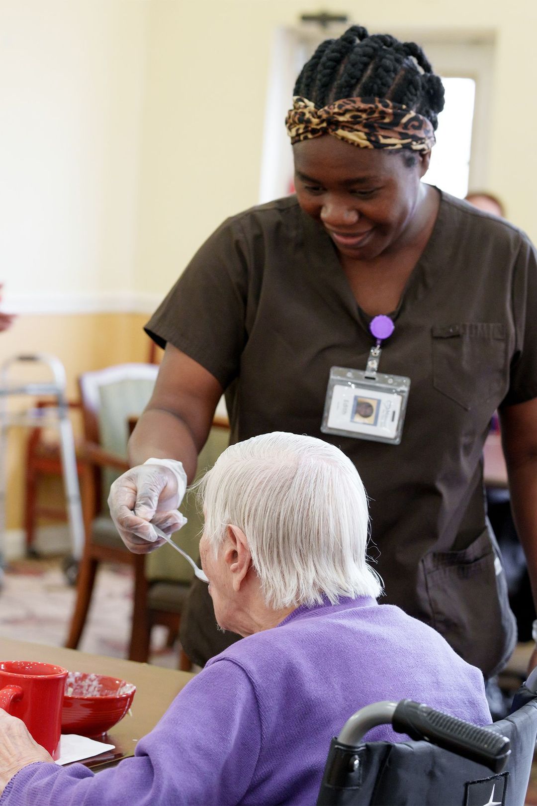 A nurse is feeding an elderly woman in a wheelchair.