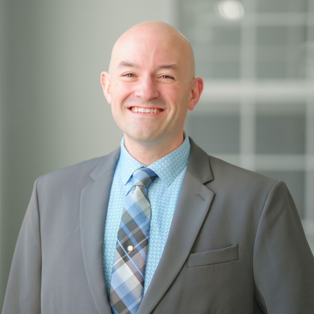 A bald man in a suit and tie is smiling for the camera.