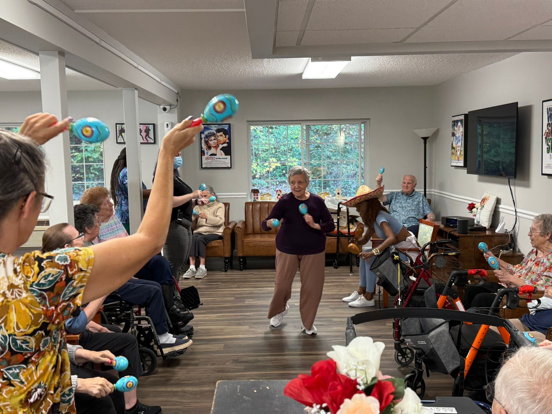 A woman is holding a green balloon in front of a group of elderly people.