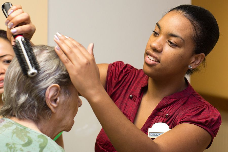 A woman is brushing another woman 's hair with a brush