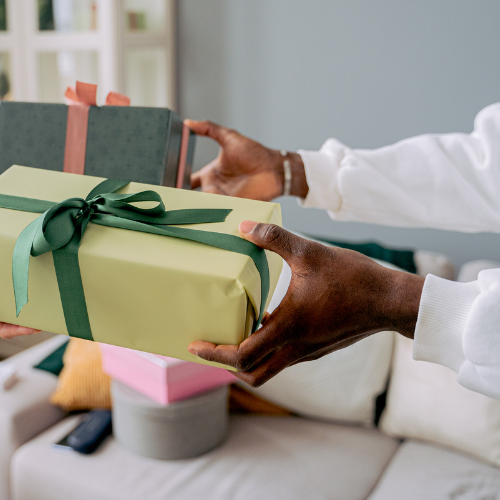 Une personne tient un coffret cadeau avec un ruban vert.