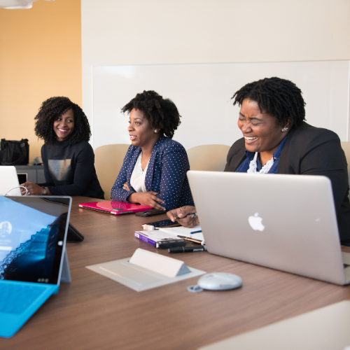 Trois femmes sont assises à une table avec des ordinateurs portables