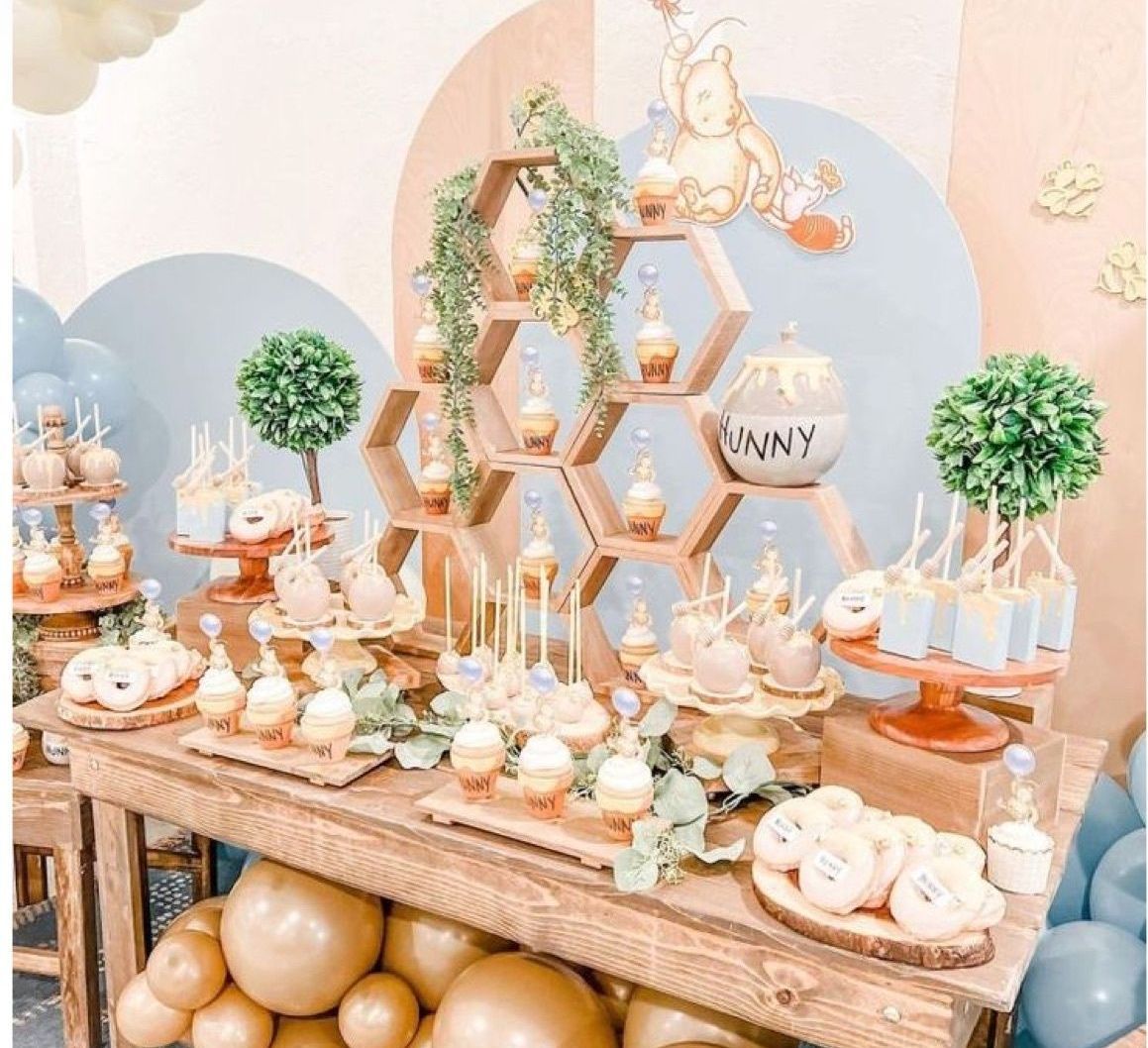 A wooden table topped with cupcakes , cake pops , and balloons.