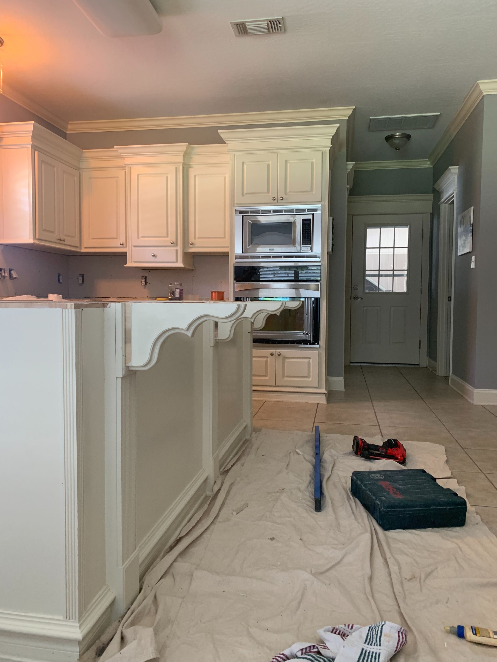 A kitchen is being remodeled with white cabinets and a microwave oven.