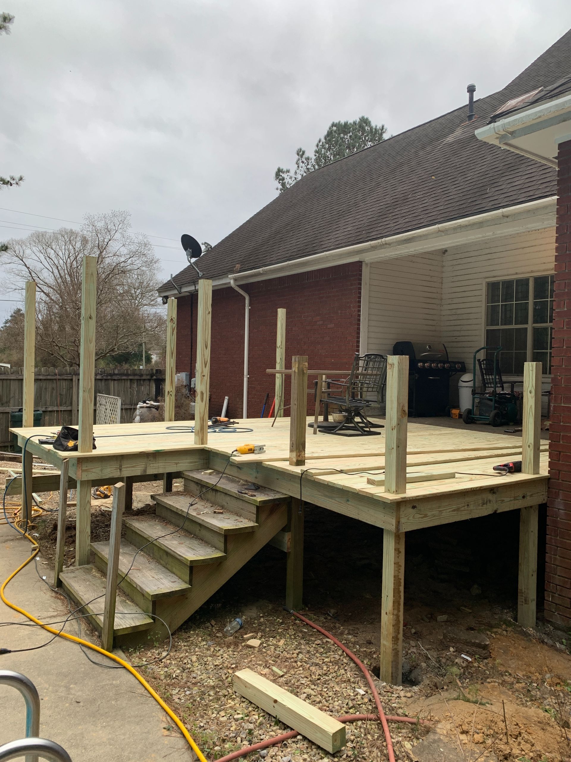 A wooden deck is being built in front of a brick house.