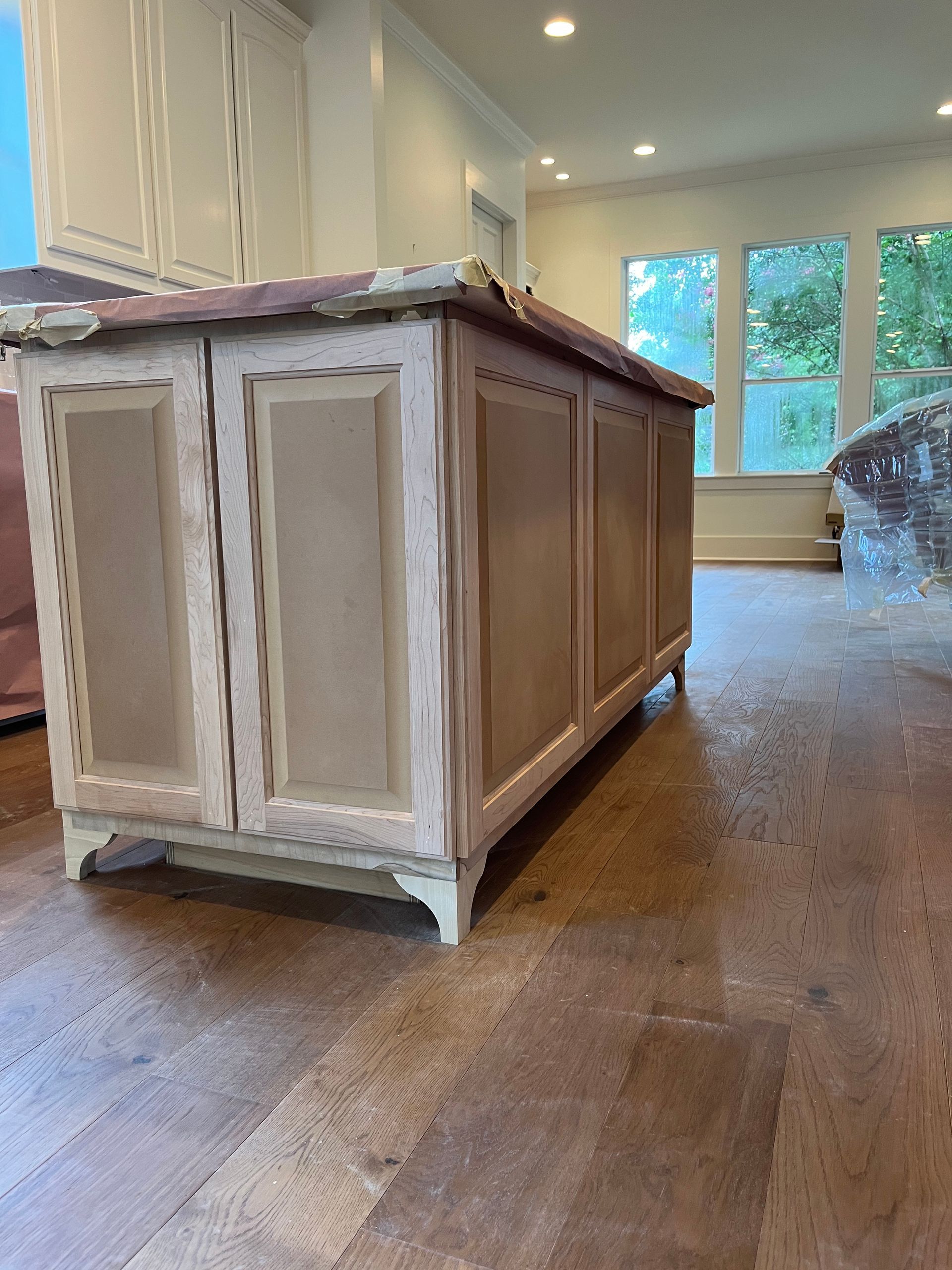 A wooden cabinet is sitting on a wooden floor in a kitchen.