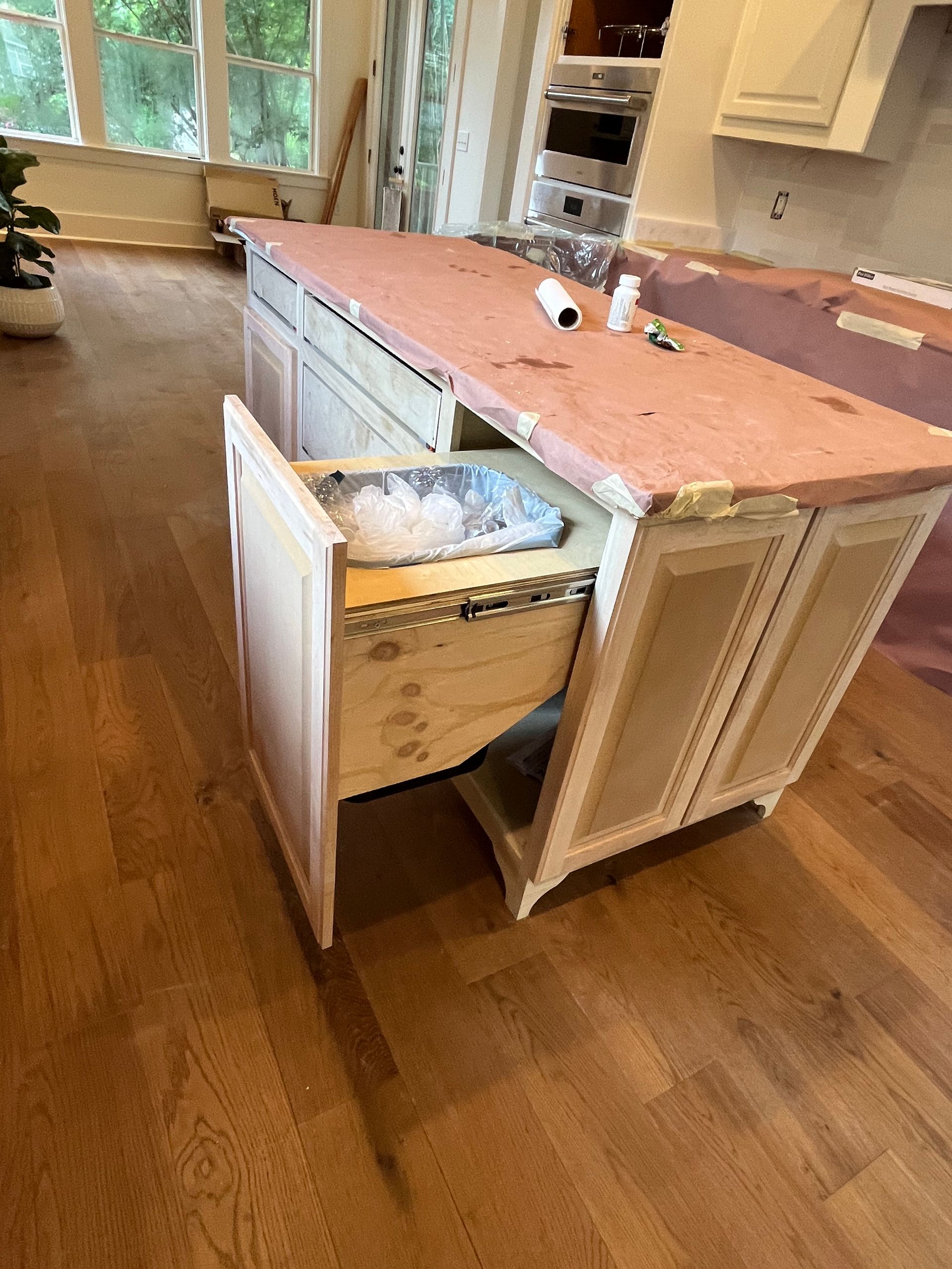 A kitchen island with a drawer open and a trash can in it.