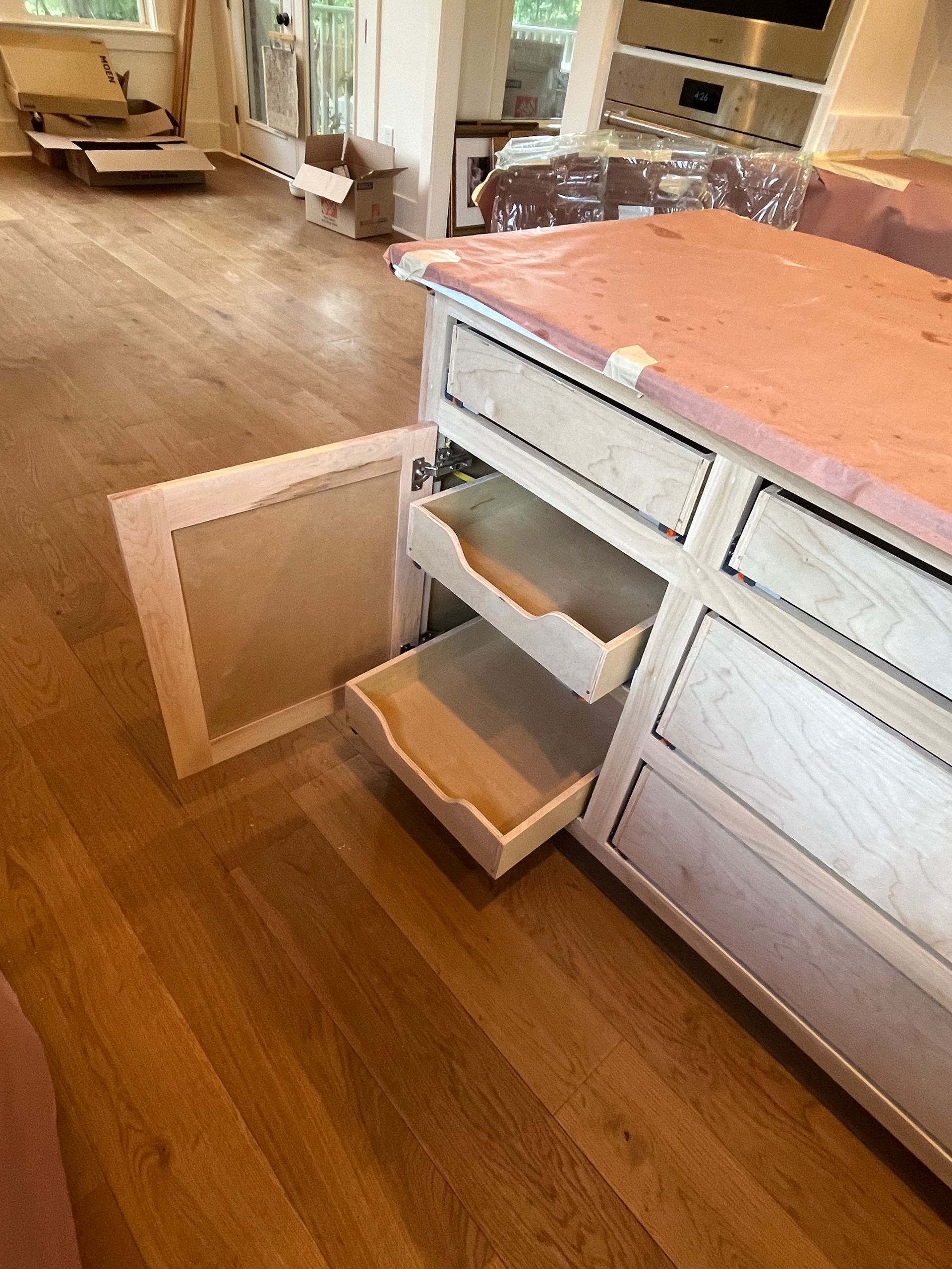 A kitchen island with drawers open and a wooden floor.