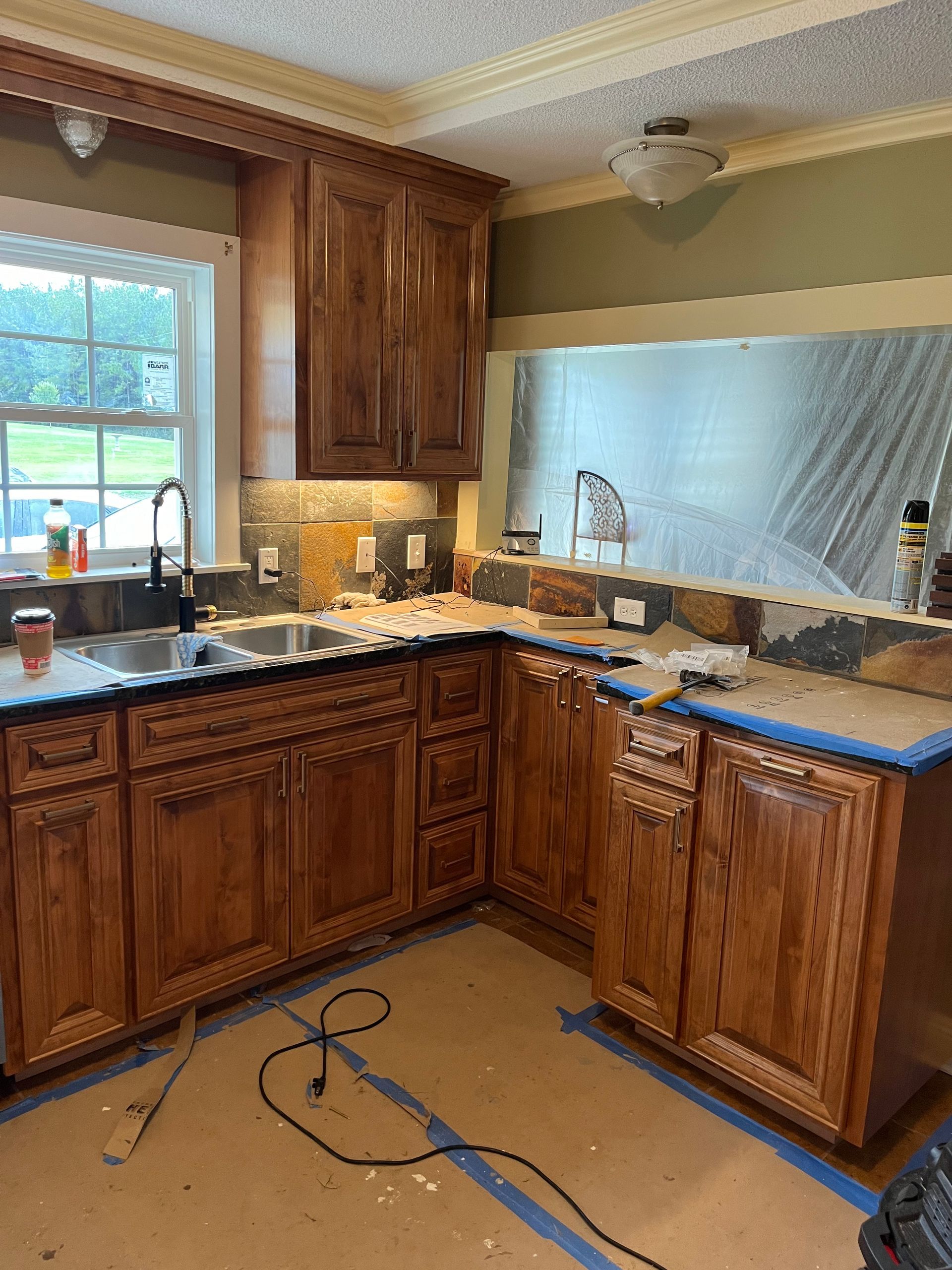 A kitchen with wooden cabinets and a sink is being remodeled.