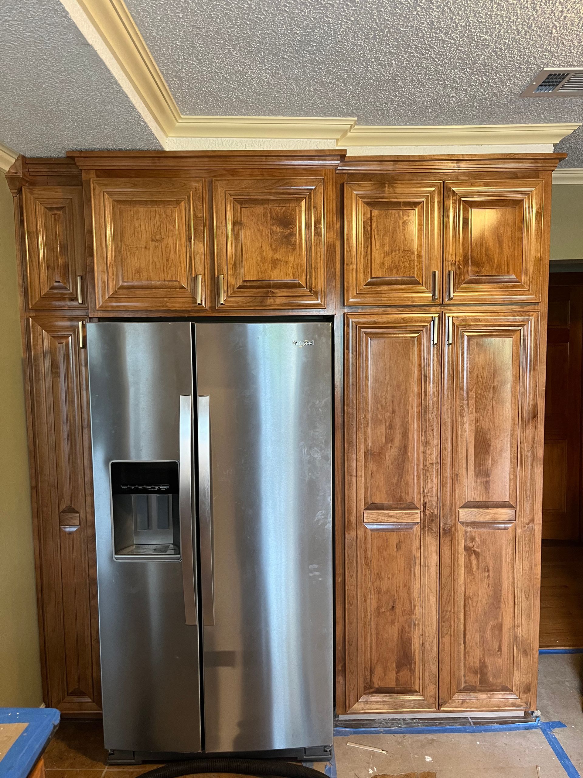 A stainless steel refrigerator is in a kitchen with wooden cabinets.