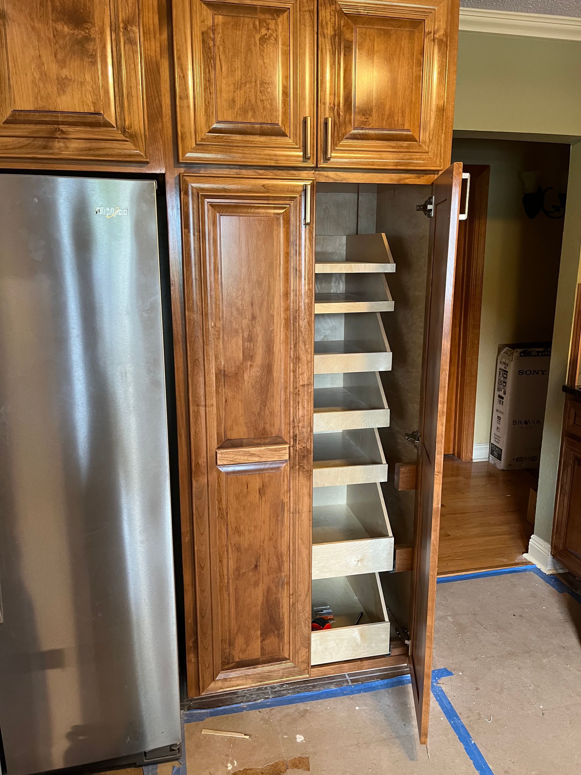 A kitchen with wooden cabinets and a stainless steel refrigerator.