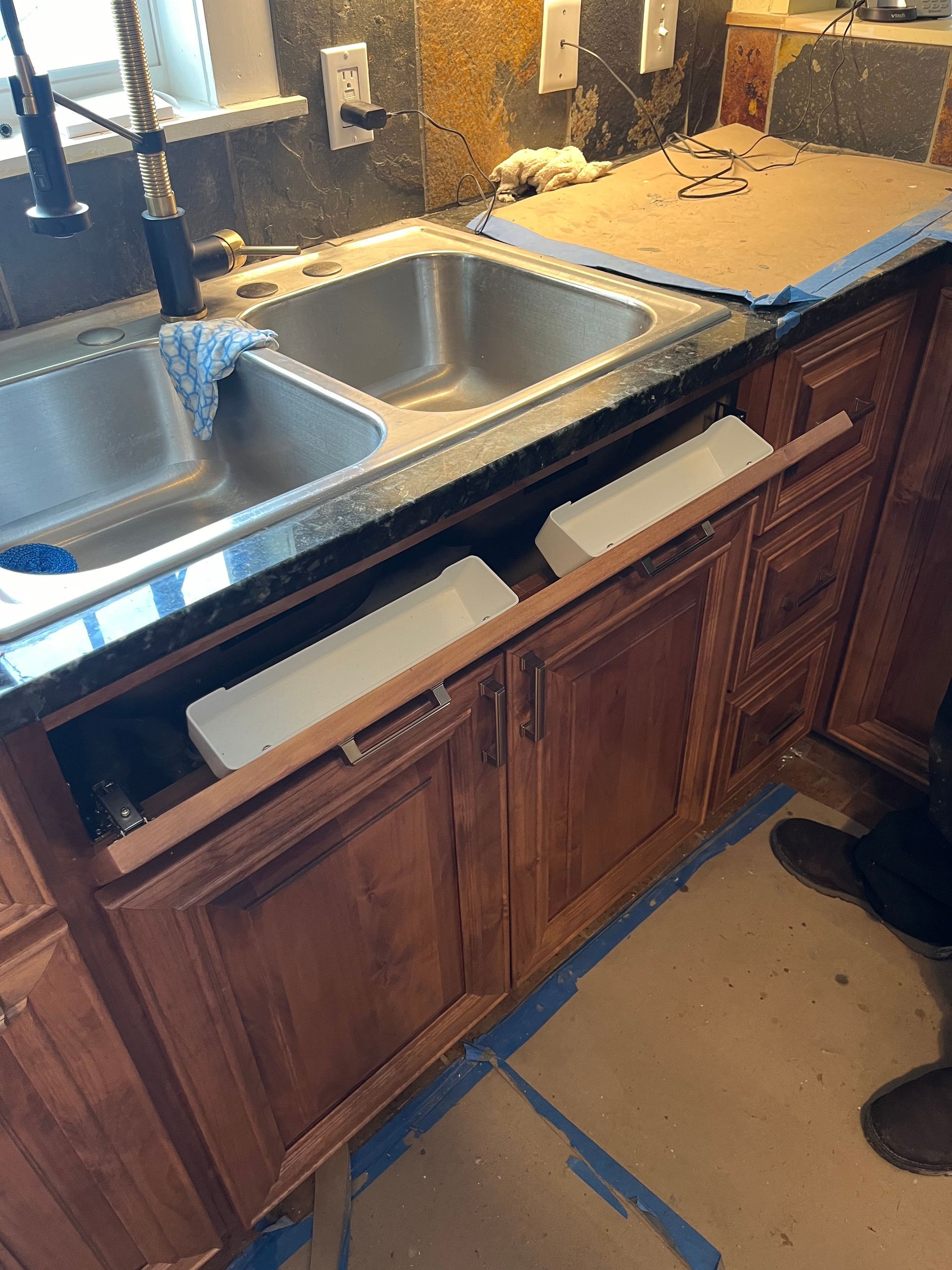 A kitchen sink with a wooden cabinet underneath it.