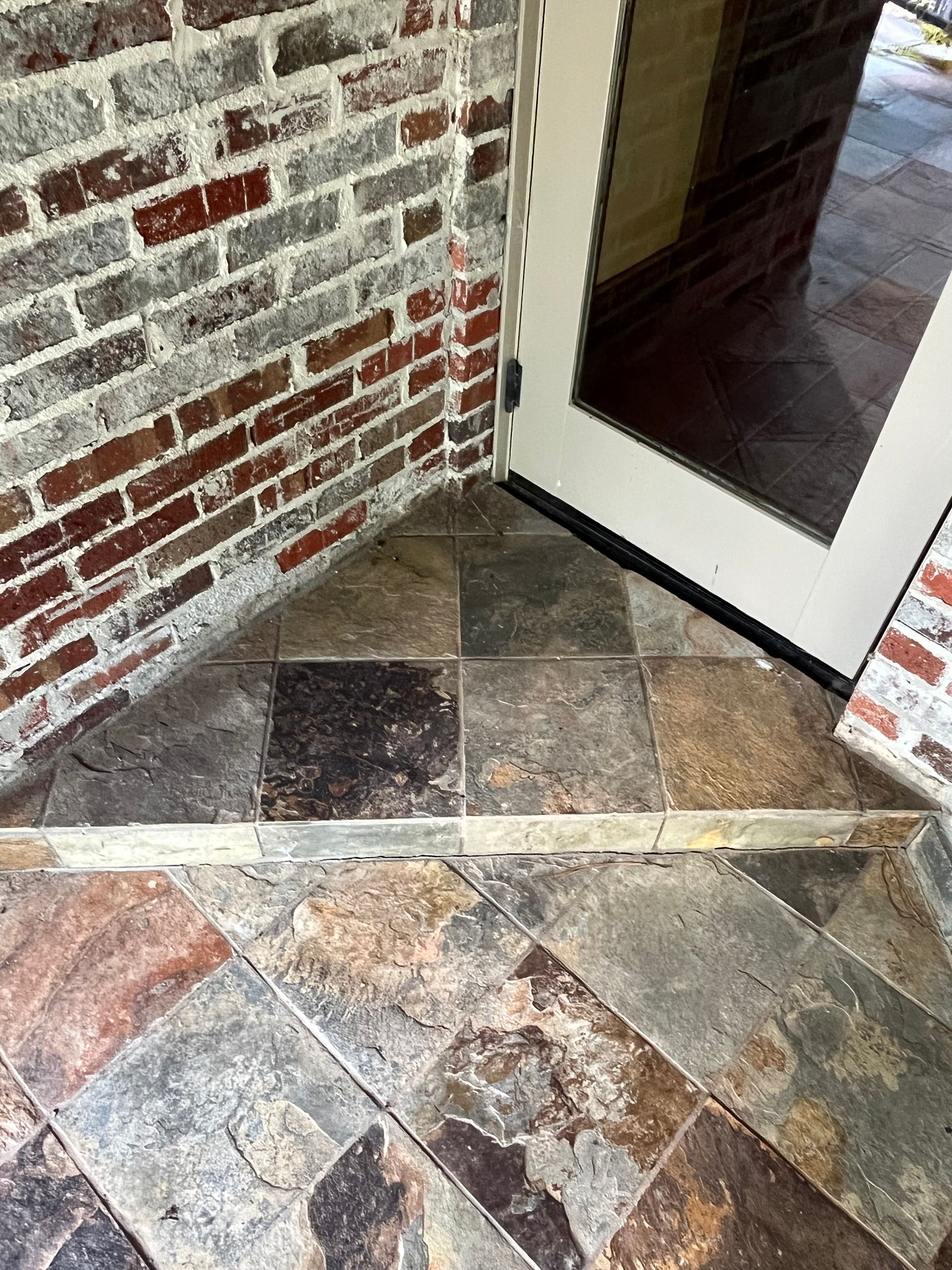 A tiled floor next to a brick wall and a door.