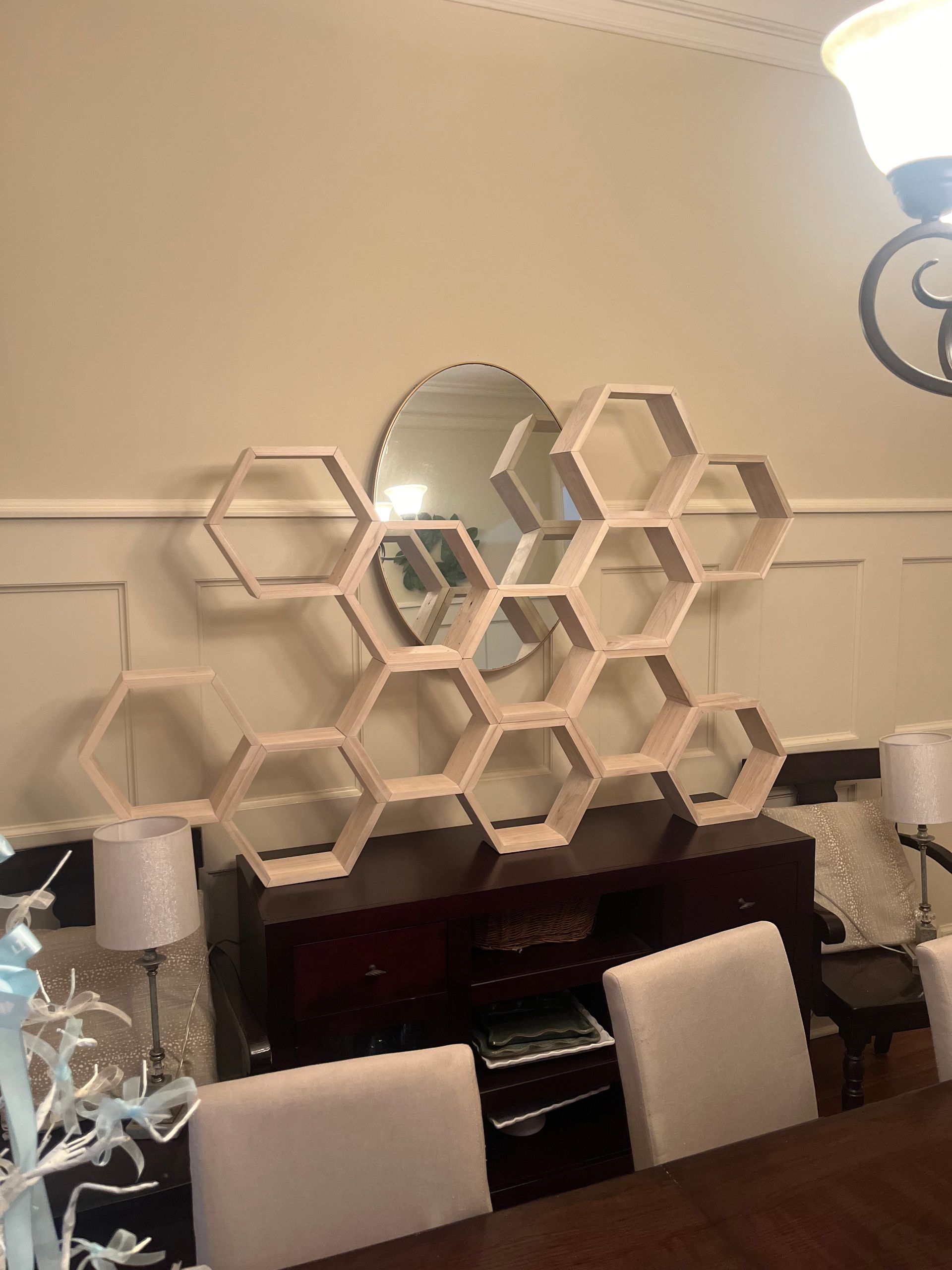 A dining room with a honeycomb shelf and a mirror