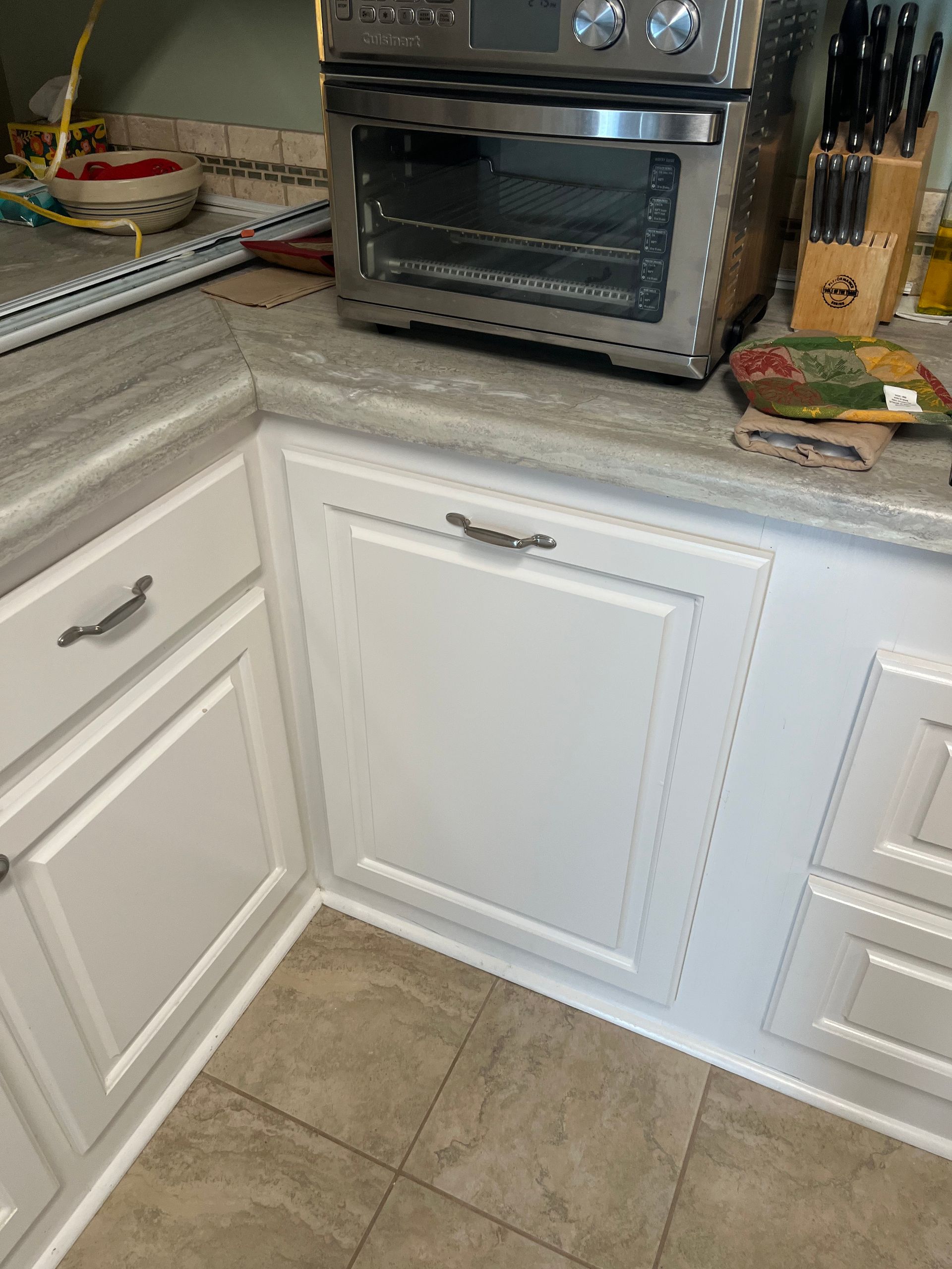 A kitchen with white cabinets and a toaster oven on the counter.