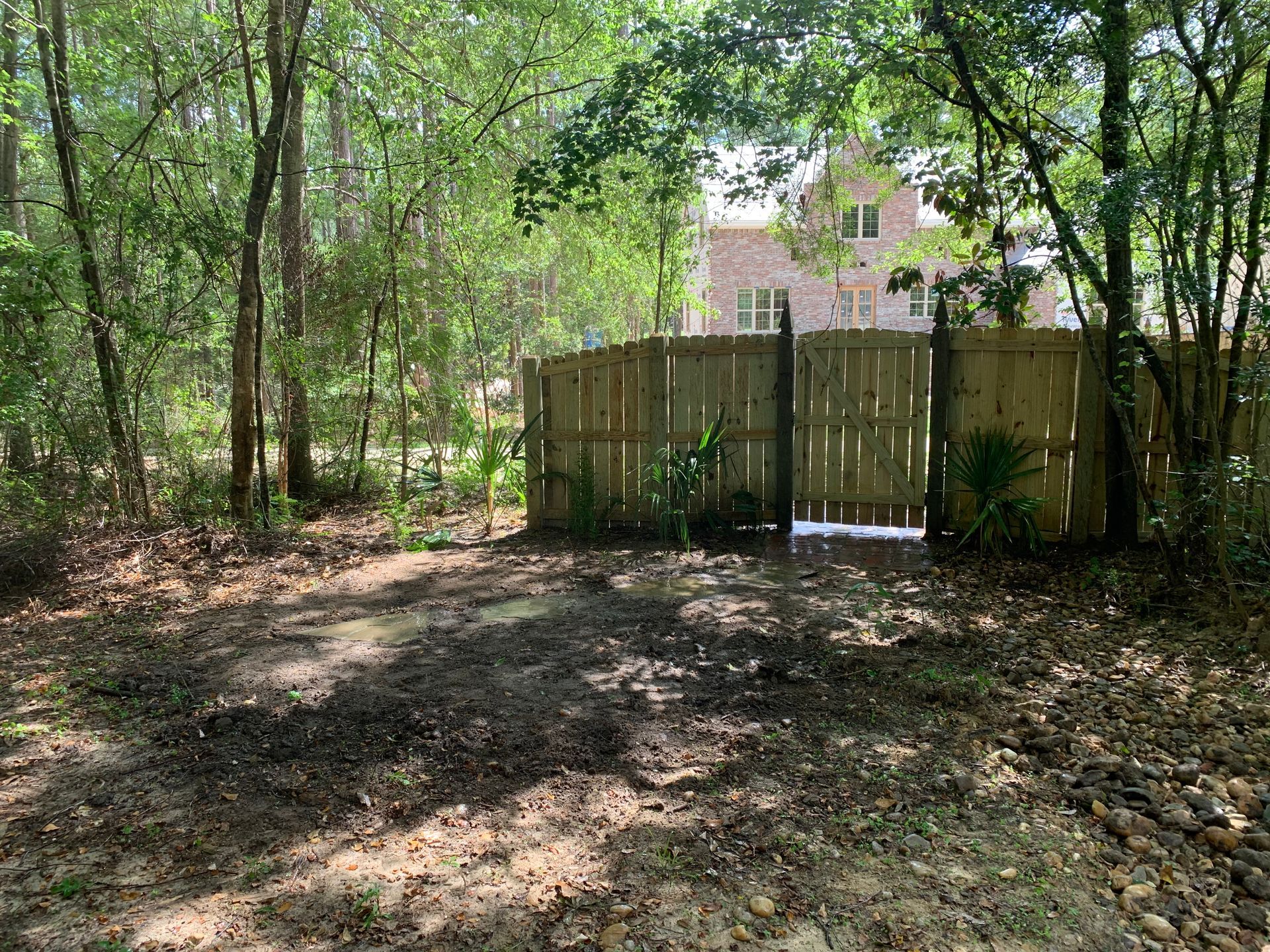 A wooden fence in the middle of a forest with a house in the background.