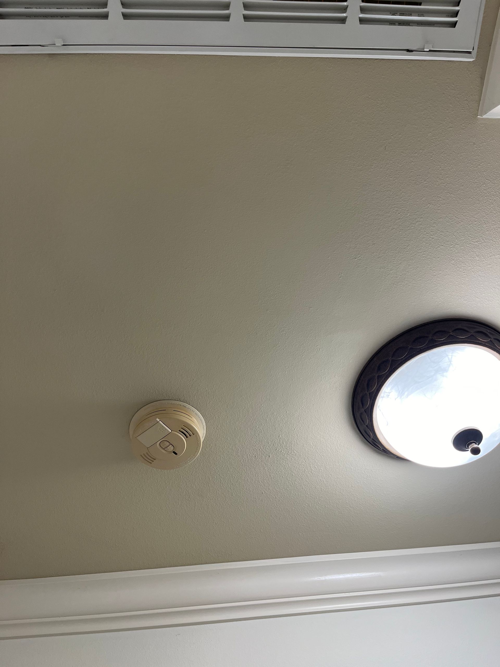 A ceiling with a smoke detector and a light on it.