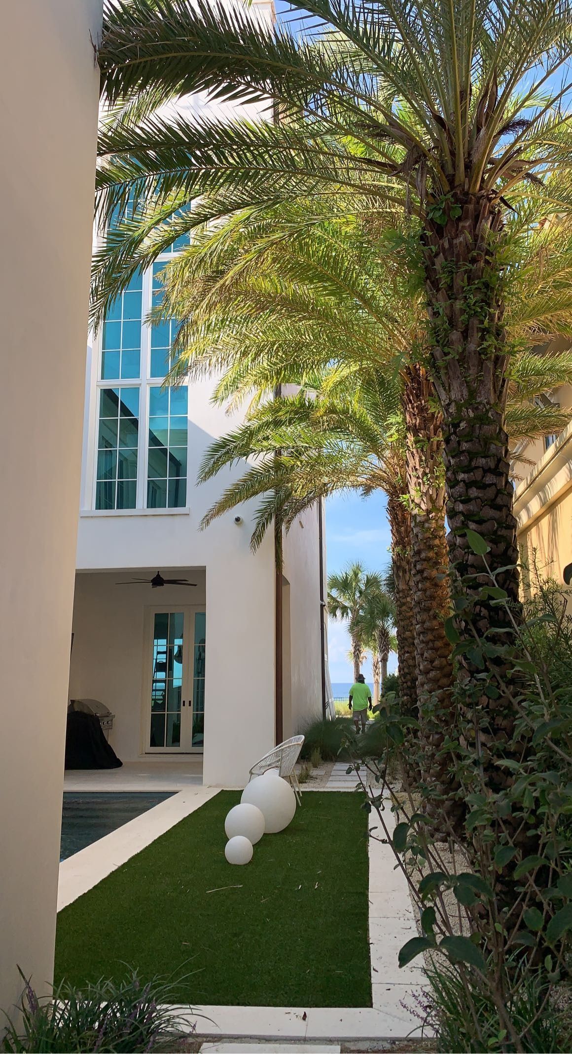 A white house with a pool and palm trees in front of it.