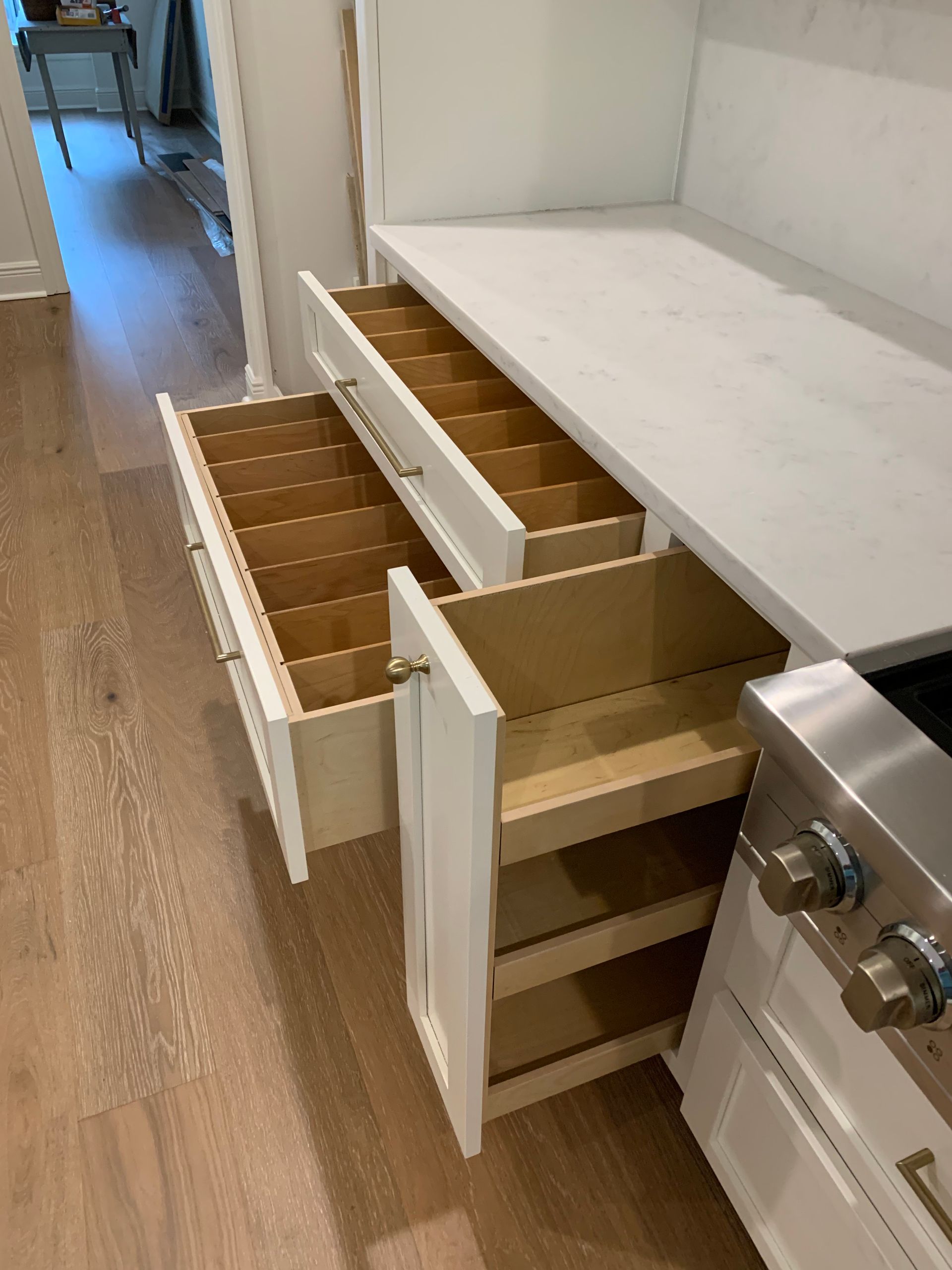 A kitchen with two drawers open and a stove.