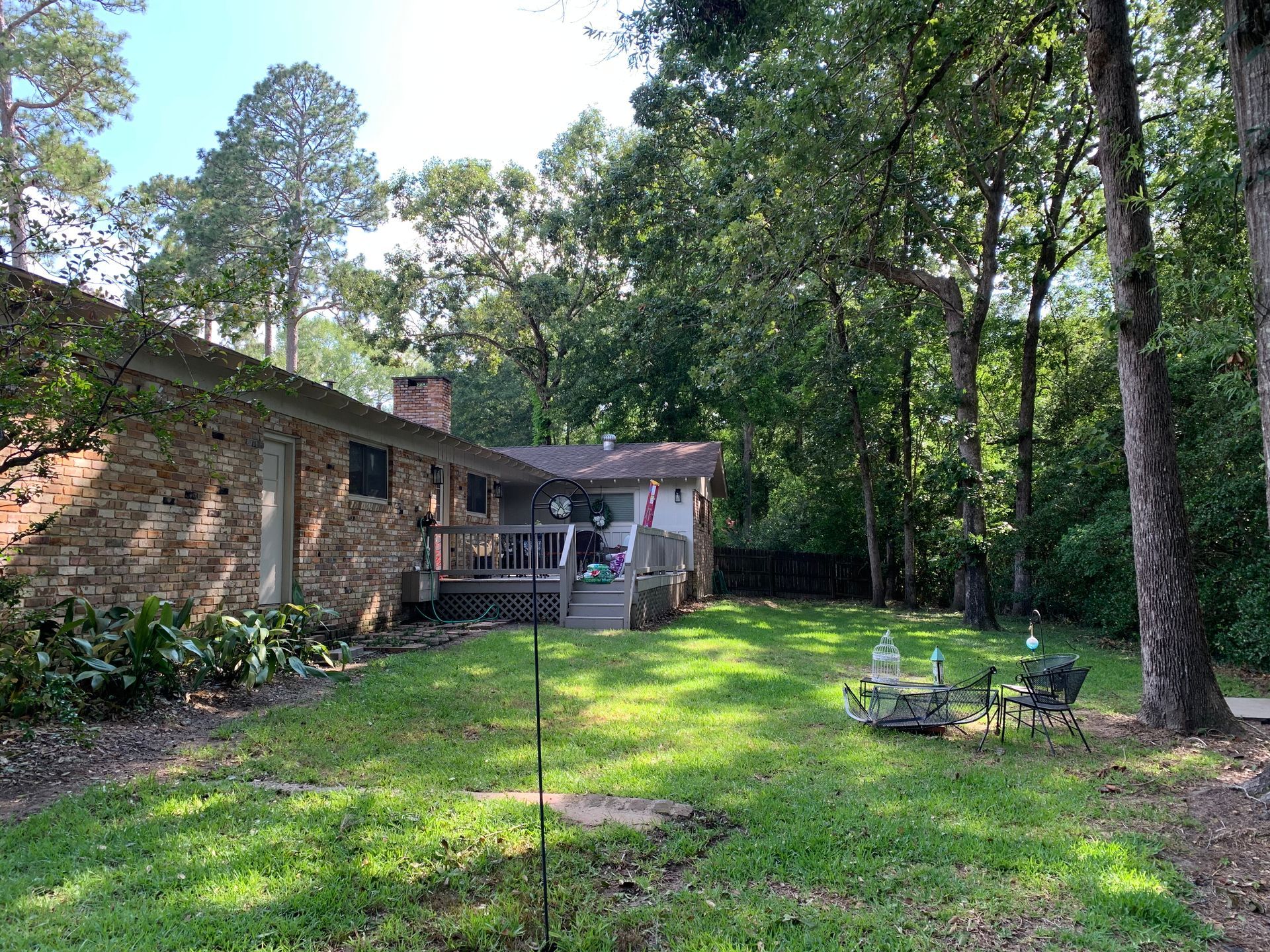 The backyard of a house with a large lawn and trees in the background.