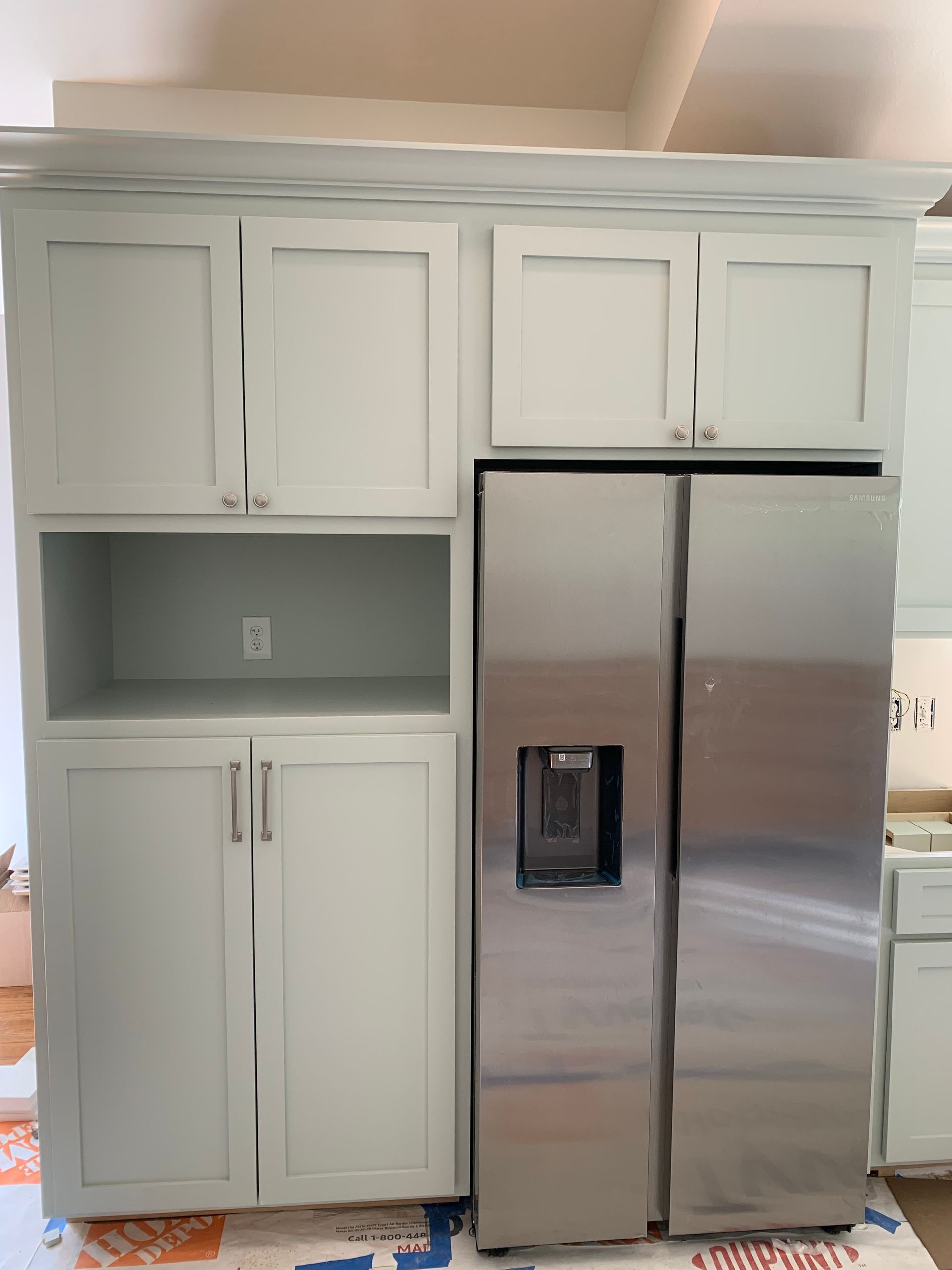 A kitchen with white cabinets and a stainless steel refrigerator