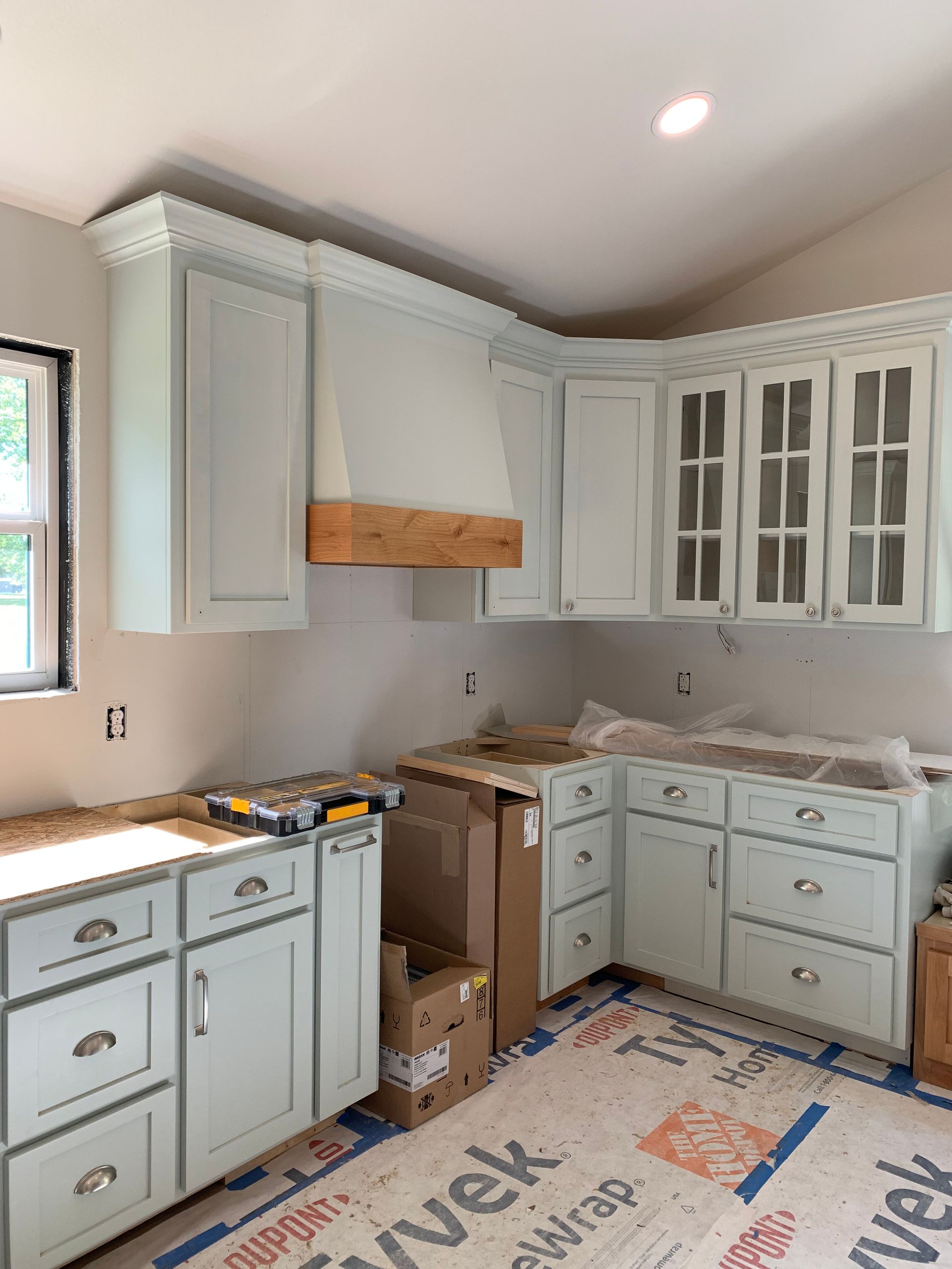 A kitchen with white cabinets and a wooden hood is being remodeled.