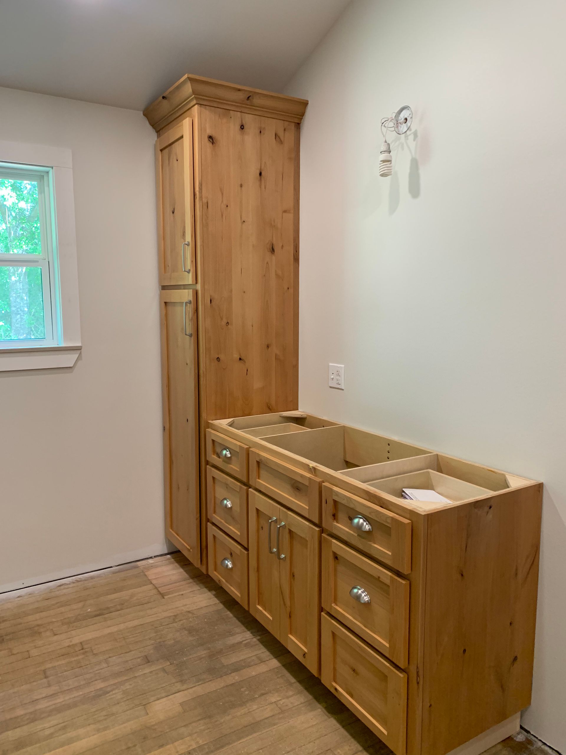 A bathroom with wooden cabinets and drawers and a window