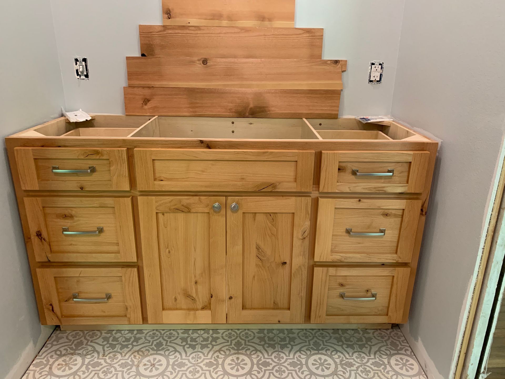 A bathroom vanity is being built with wooden cabinets and drawers.