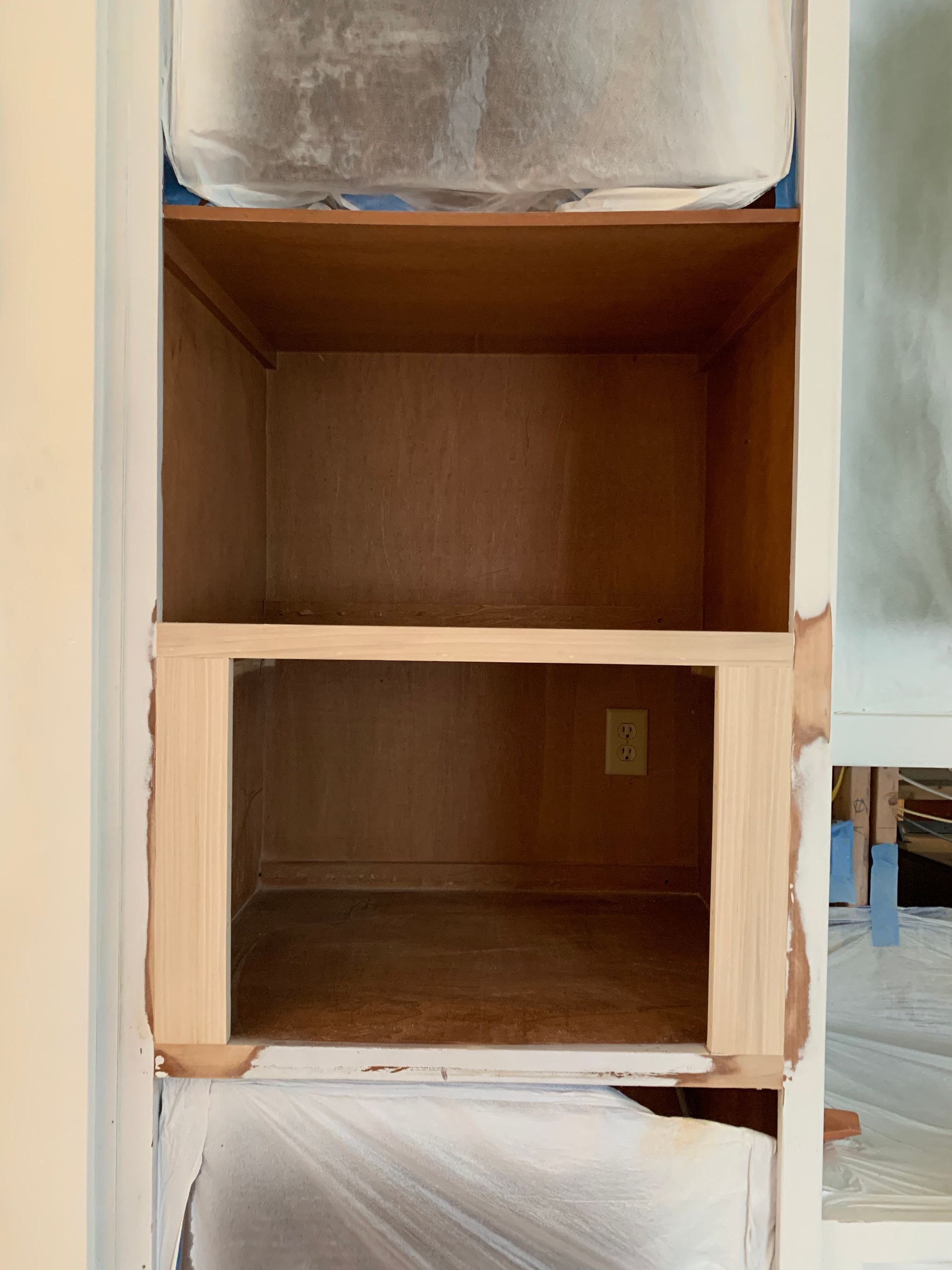 An empty shelf in a closet that is being painted