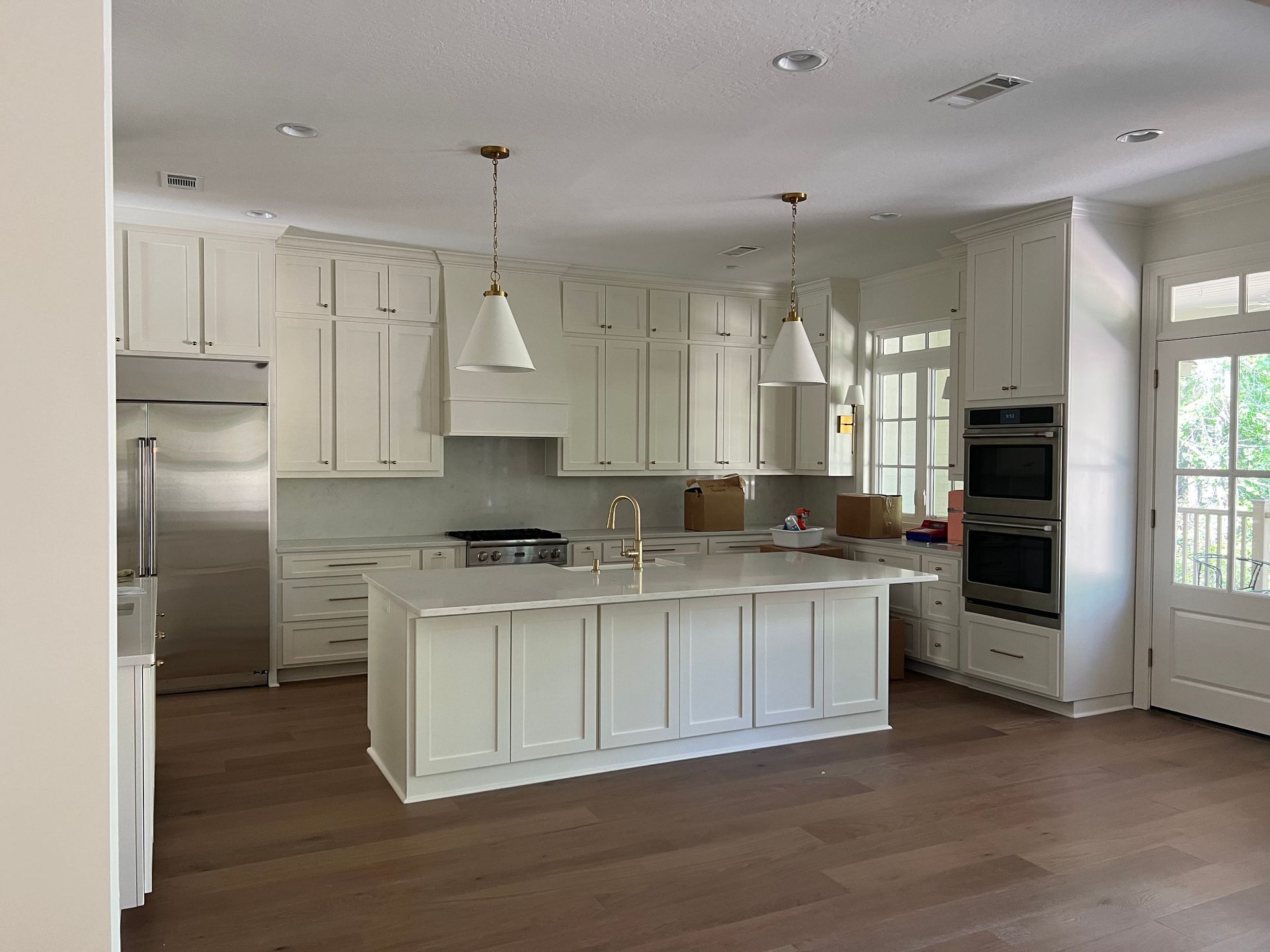 A kitchen with white cabinets , stainless steel appliances , and a large island.