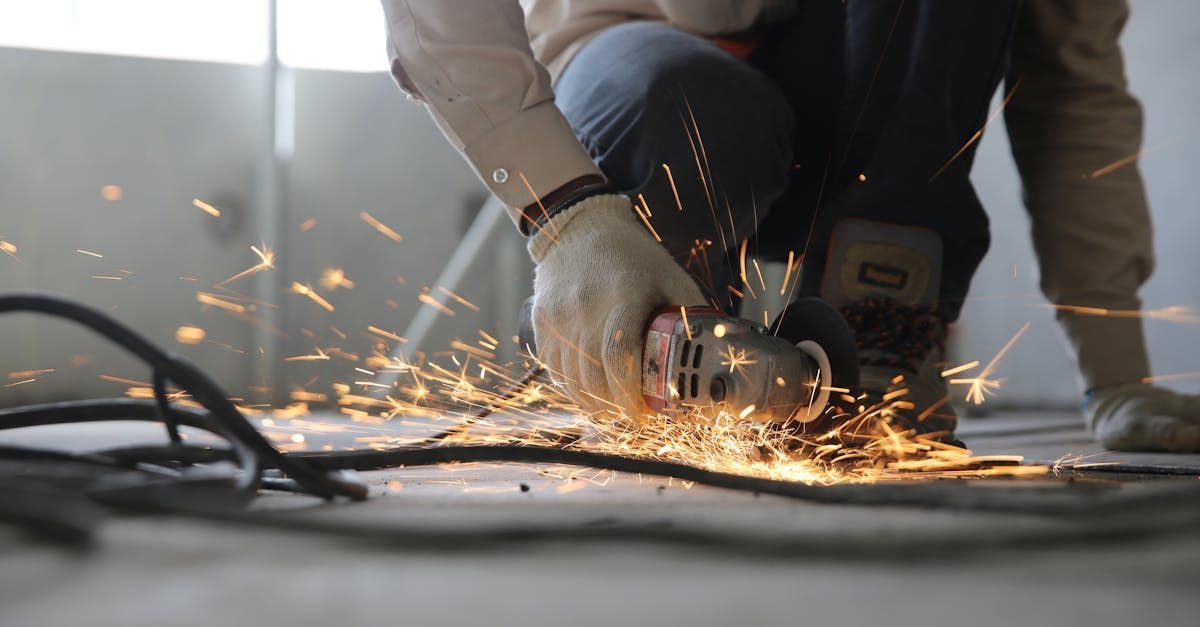 A man is using a grinder to cut a piece of metal.