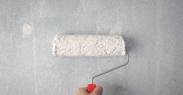 A person is painting a wall with a paint roller.