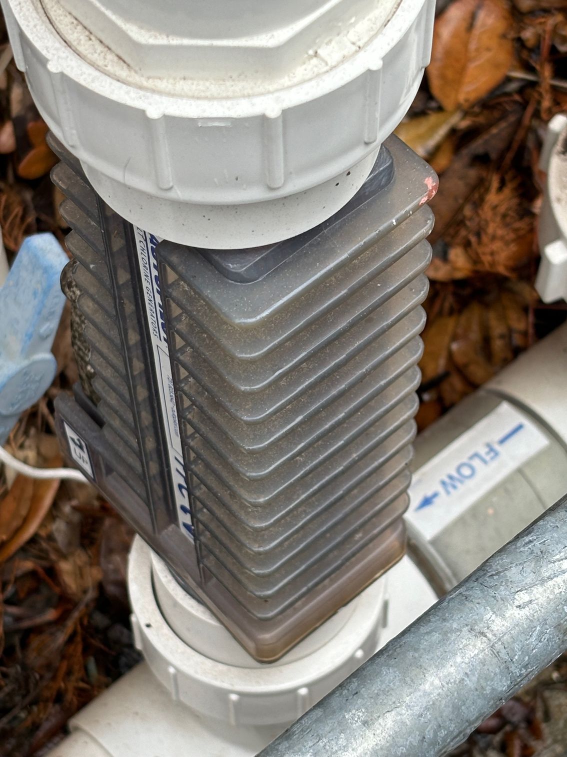 A woman wearing a face shield is cleaning a swimming pool.