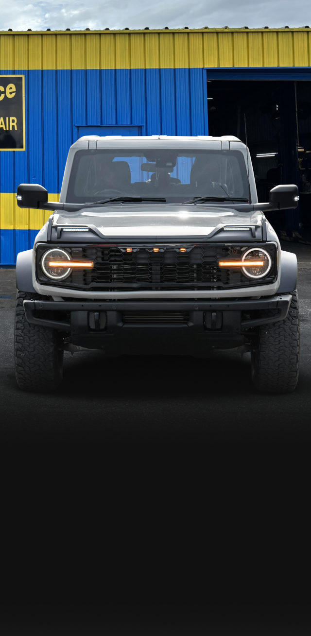 Gray Ford Bronco parked in front of a blue and yellow building. | Dacey's Place