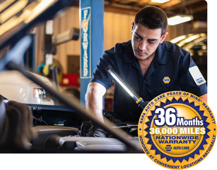 Mechanic in blue shirt examining engine with light, in garage. 36-month, 36,000-mile warranty graphic. | Dacey’s Place