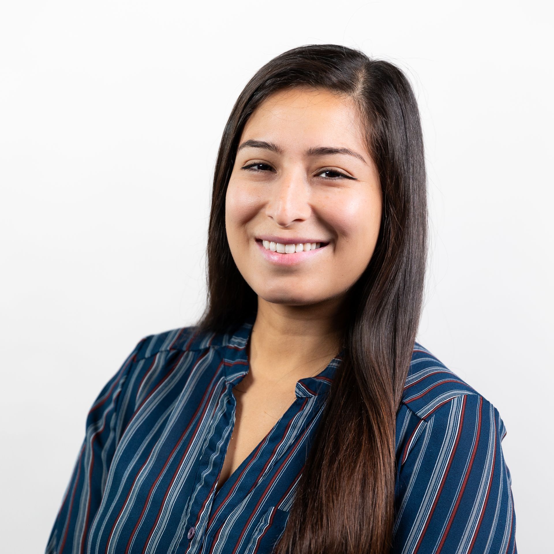 A woman in a blue striped shirt is smiling for the camera.