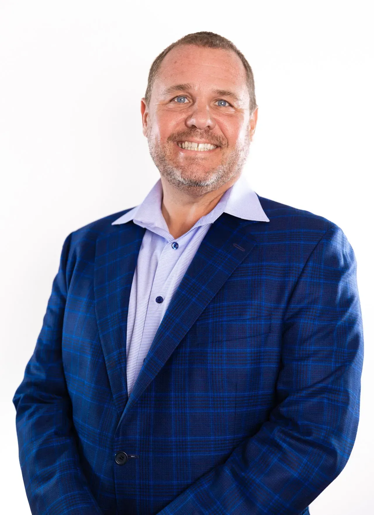 A man in a blue suit and white shirt is smiling for the camera.
