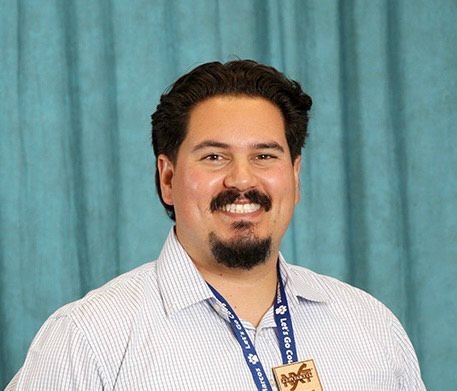 A man with a beard and a medal around his neck is smiling.