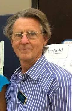 A man wearing glasses and a striped shirt is posing for a picture.