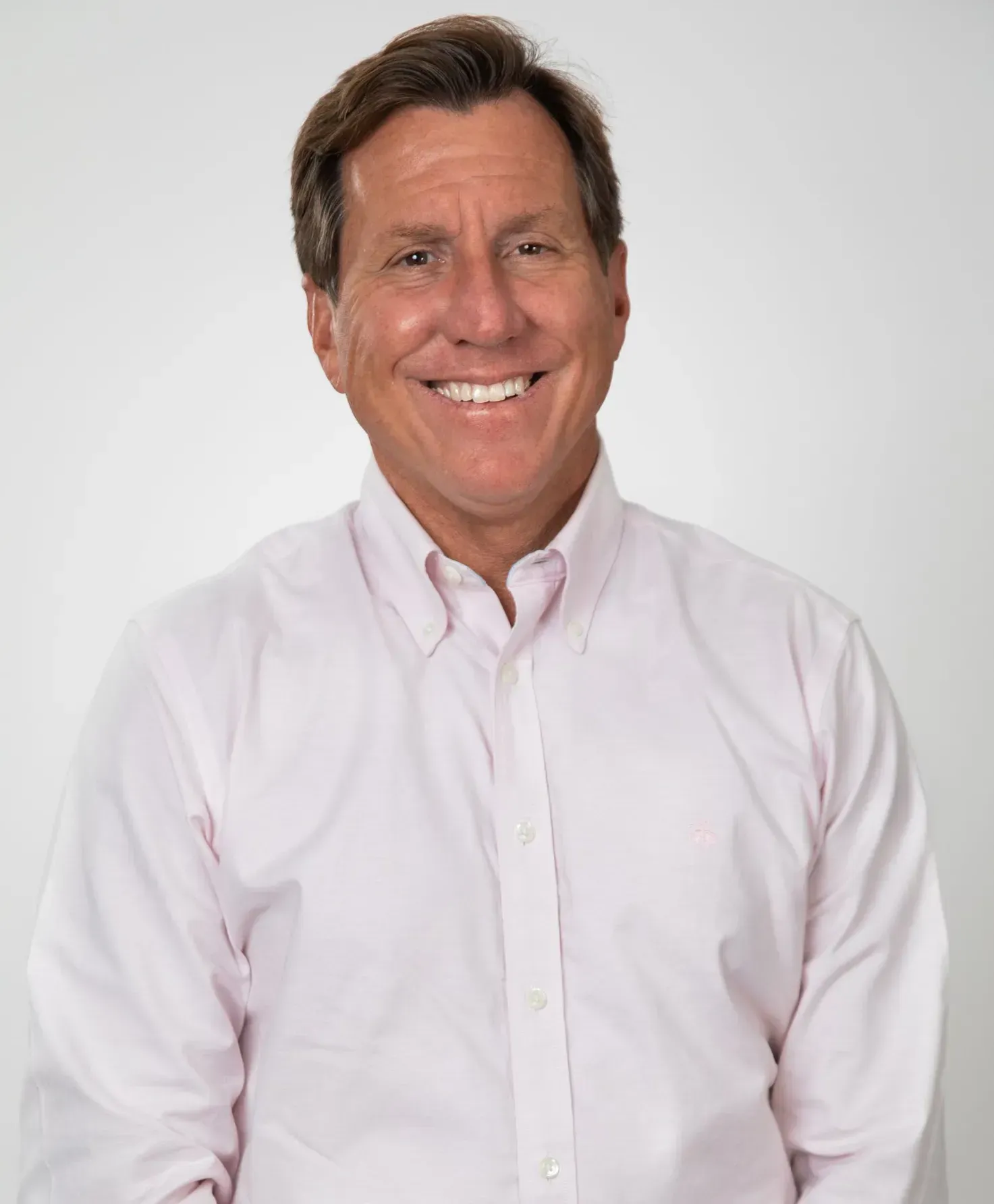 A man in a pink shirt is smiling for the camera