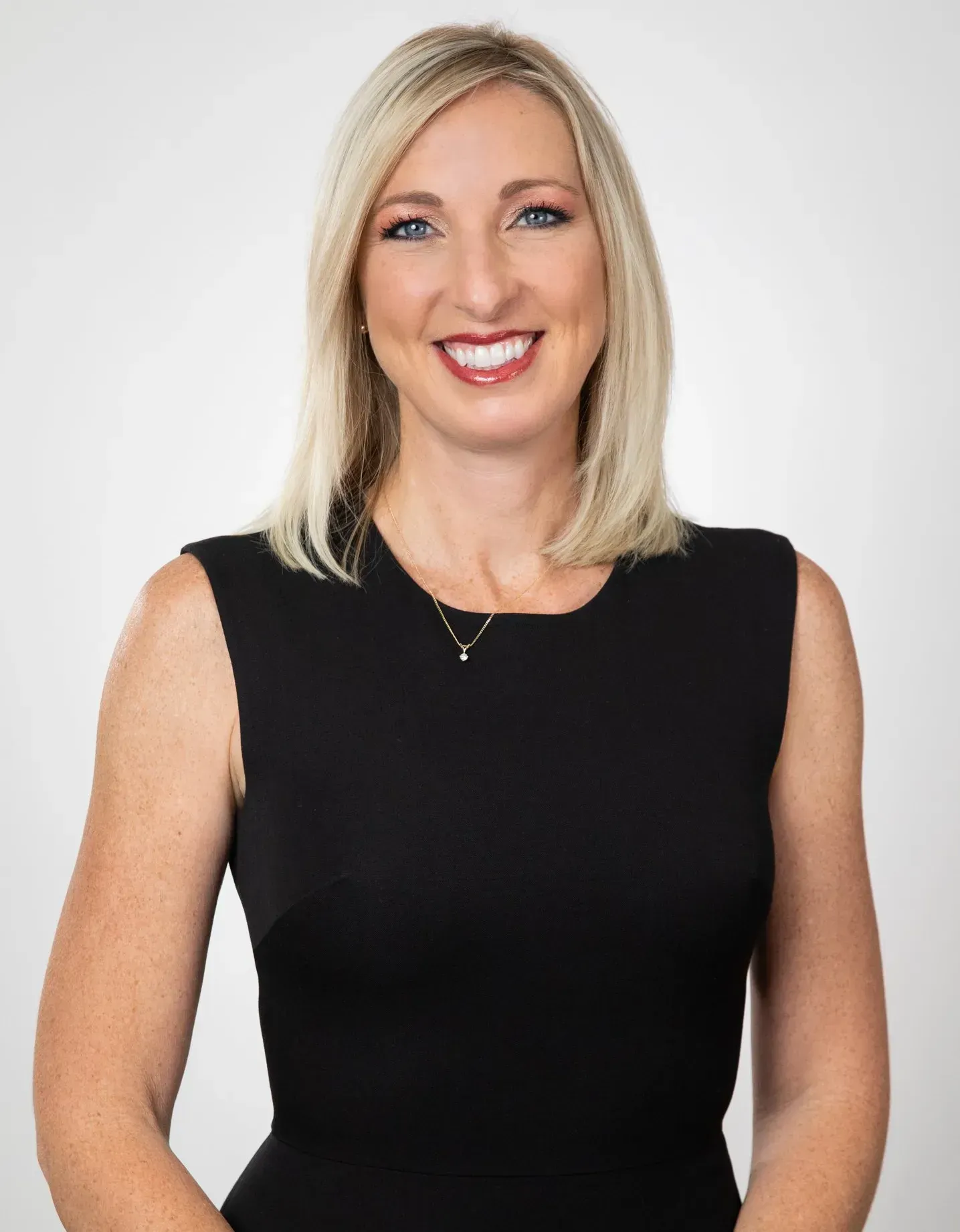 A woman in a black dress is smiling for the camera