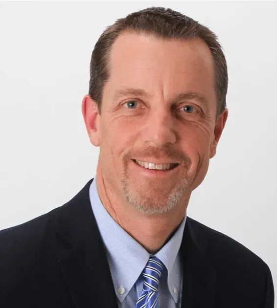 A man in a suit and tie is smiling for the camera