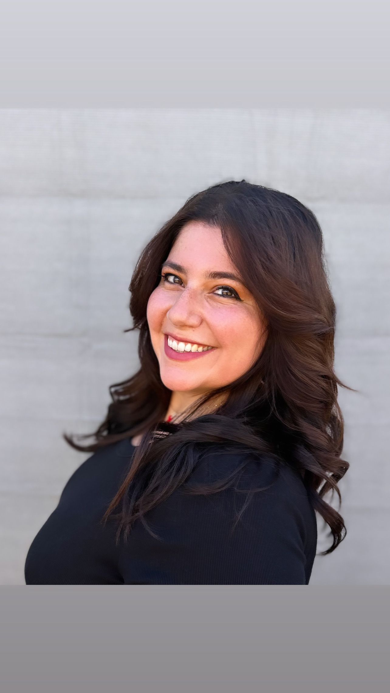 A woman in a black shirt is smiling for the camera.