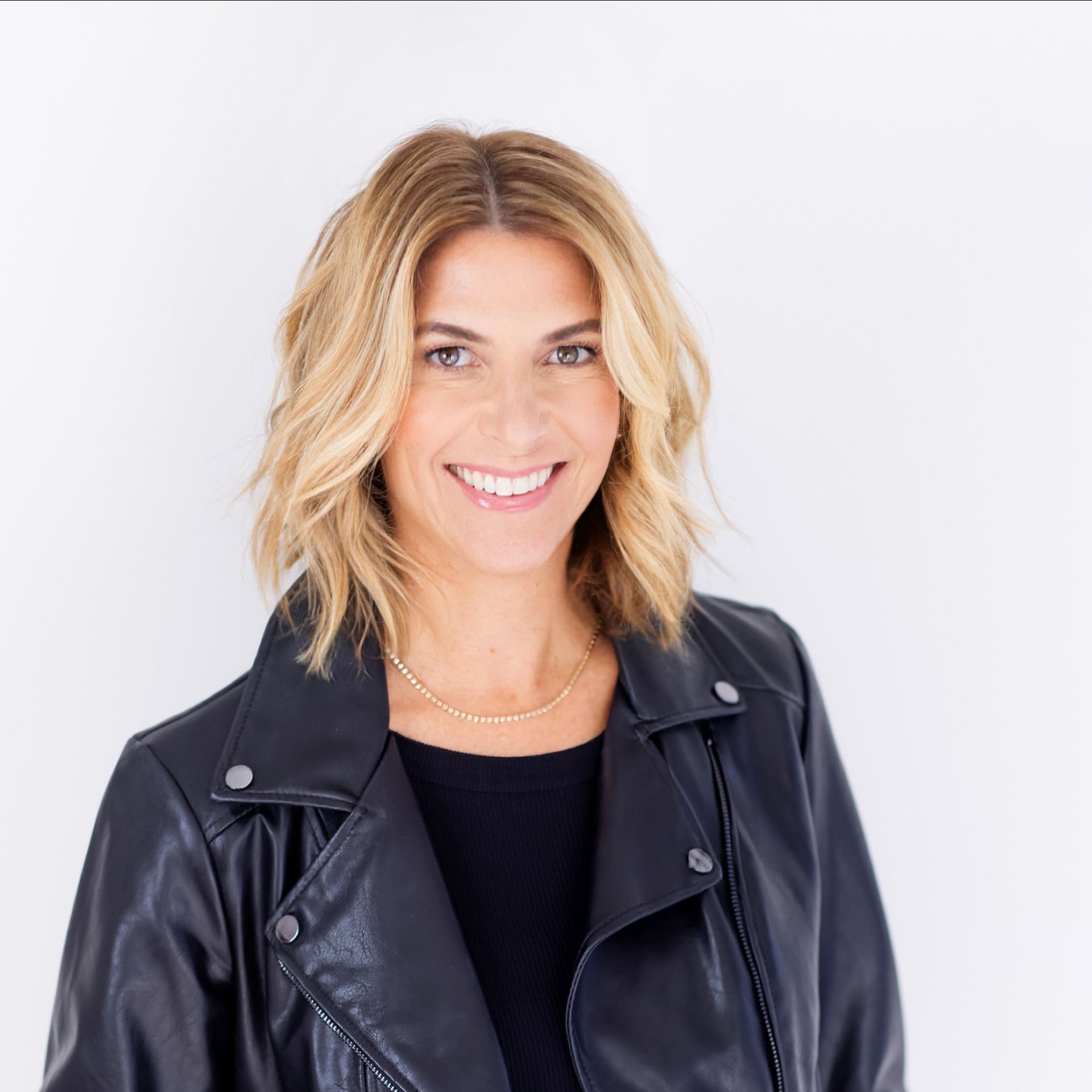 A woman wearing a black leather jacket is smiling for the camera