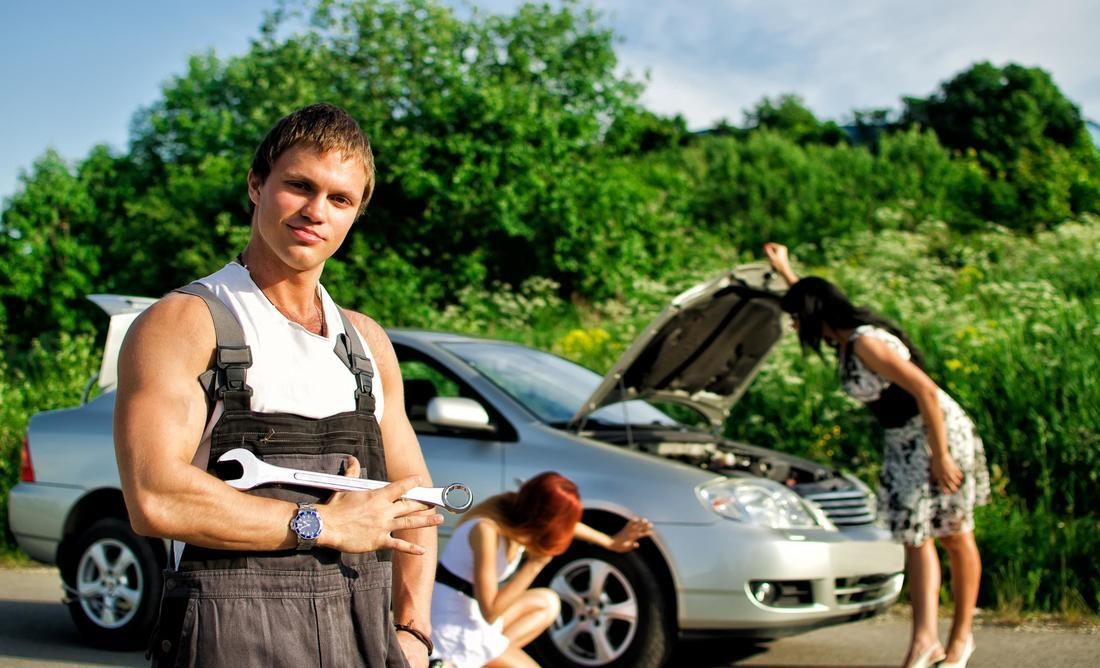 A man and a woman are standing next to a broken down car.