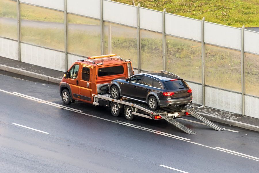 A tow truck is towing a car on a highway.